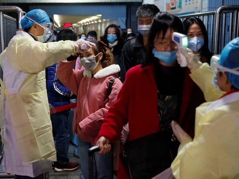 Medical workers take the temperature of passengers after they got off the train in Jiujiang, Jiangxi province, China, as the country is hit by an outbreak of a new coronavirus, January 29, 2020.