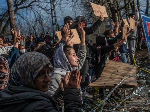 Migrants hold placards as they demonstrate, waiting at the buffer zone in front of the Pazarkule border crossing to Greece, in Edirne on March 3.