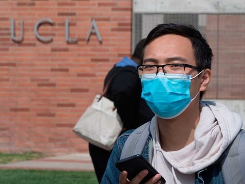 A student wears a face mask to protect against the COVID-19 (Coronavirus) as he leaves the campus of the UCLA college in Westwood, California on March 6, 2020. Three UCLA students are currently being tested for the COVID-19 (coronavirus) by the LA Departement of Public Health, according to the UCLA Chancellor Gene Block. / AFP / Mark RALSTON