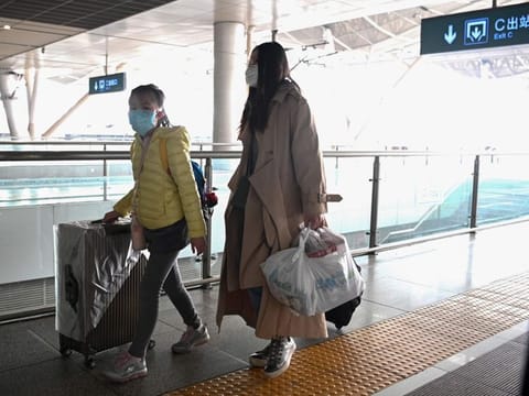 Mask-clad passengers alight from their train at the railway station in Wuhan, China's central Hubei province on March 10, 2020.