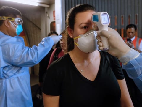 Medical staff check passengers' temperature upon their arrival at Jorge Chavez International Airport in Callao, west of Lima, on a late flight from Spain on March 11, 2020.