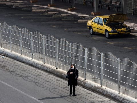 A woman waits for a taxi at an empty taxi in Tehran. Iran is scrambling to control one of the worst outbreaks of the coronavirus in the world.