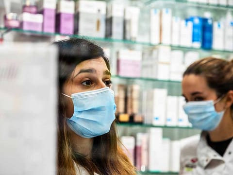 Pharmaceutical workers wear face masks to serve customers in a pharmacy. Photo of illustrative purpose only