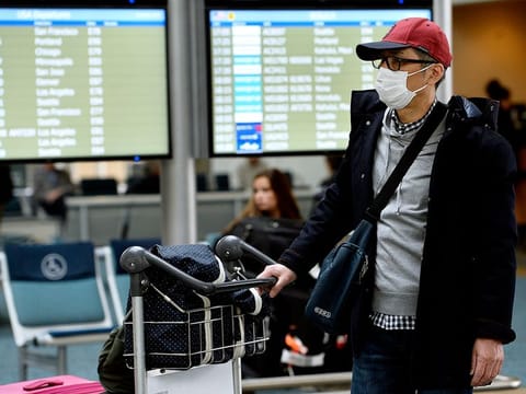 A traveller wearing a protective mask walks through Vancouver International Aiport (YVR) in Vancouver, British Columbia, Canada, on Tuesday, March 17, 2020.