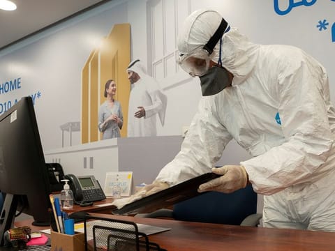 A worker wearing a protective suit wipes down a key board in a local bank as a precaution against the coronavirus disease (COVID-19), following the outbreak, in Kuwait City.