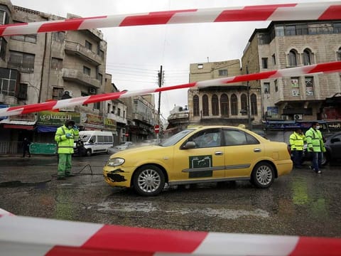 Greater Amman Municipality employees sanitize cars at street amid concerns over the coronavirus disease (COVID-19) spread, outside al Husseini mosque in downtown Amman, Jordan, March 20, 2020.
