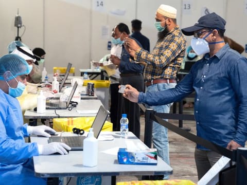 Expatriates, arriving to Kuwait, stand a safe distance apart to give their details to ministry of health officials in a makeshift coronavirus testing centre, at Kuwait International Fairgrounds in Mishref, Kuwait on March 18.