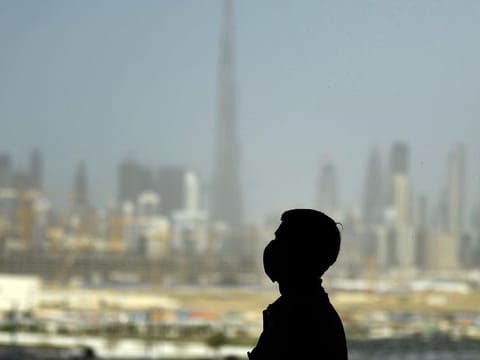 File image: A man wearing a protective mask stands at a racetrack overlooking Dubai