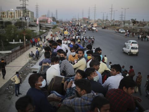 In this Saturday, March 28, 2020, photo, Indian migrant workers sit atop a bus, provided by the government, as others walk along an expressway to their villages following a lockdown amid concern over spread of coronavirus in New Delhi, India. Over the past week, India’s migrant workers - the mainstay of the country’s labor force - spilled out of big cities that have been shuttered due to the coronavirus and returned to their villages, sparking fears that the virus could spread to the countryside. It was an exodus unlike anything seen in India since the 1947 Partition, when British colothe subcontinent, with the 21-day lockdown leaving millions of migrants with no choice but to return to their home villages. (AP Photo/Altaf Qadri)