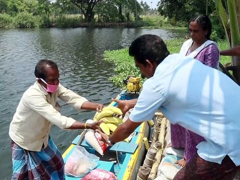 A boatman sells essential food items including food grains, vegetables and fruits, to families in Alappuzha, Kerala.