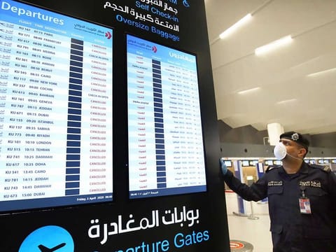 A Kuwaiti policeman wearing a mask stands by the flight takeoff board, at the Kuwait International Airport Terminal 4, on April 3, 2020 amid the coronavirus COVID-19 pandemic crisis.