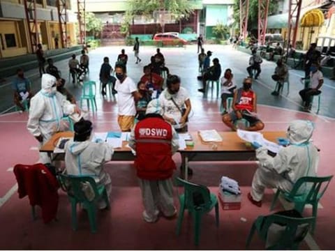 Personnel from the Philippines' Department of Social Welfare and Development (DSWD), wearing personal protective equipment, distribute the cash assistance under the Social Amelioration Program (SAP) to members of the Tricycle Operators’ and Drivers’ Association (TODA) Federation of Pasay City.