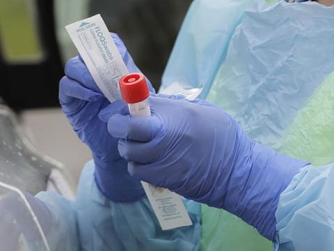 Picture for illustrative purposes: A nurse holds a vial and a swab at a coronavirus testing station