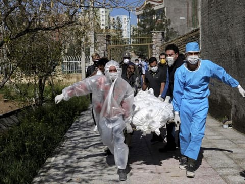 In this March 30 file photo, people carry the body of a victim who died after being infected with the new coronavirus at a cemetery just outside Tehran, Iran. Across the Middle East and parts of South Asia, bereaved families have faced traumatic restrictions on burying their dead amid the pandemic.