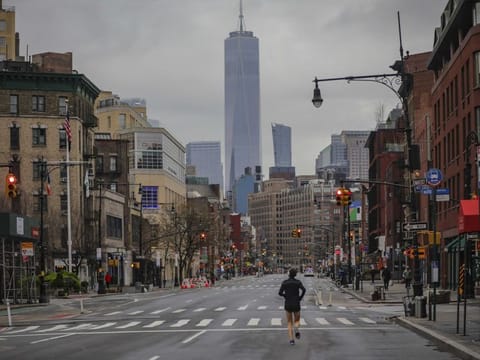 A lone jogger run on a partially empty 7th Avenue, resulting from citywide restrictions calling for people to stay indoors and maintain social distancing in an effort to curb the spread of COVID-19 on March 28, in New York.