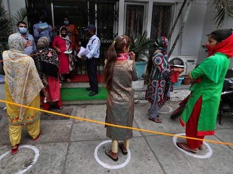 Indians queue up outside a bank to withdraw money during lockdown in Jammu, India, Tuesday, April 7, 2020.