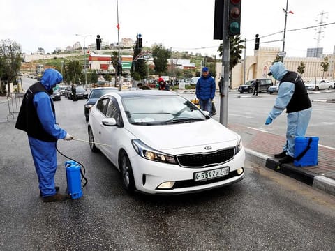 Palestinian workers sanitise cars during a home-confinement order to prevent the spread of the coronavirus disease (COVID-19), in Hebron in the Israeli-occupied West Bank, on April 7, 2020.
