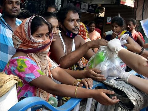 Poor and homeless people get essential food stuffs distributed buy NGO volunteers during the lockdown amid the coronavirus pandemic in the eastern Indian city of Kolkata in West Bengal on Friday.