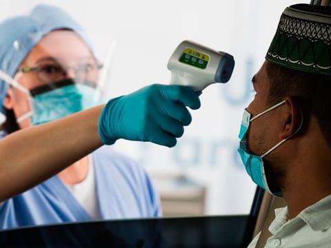 A health-care worker checks a man's temperature at a drive-thru testing facility in Abu Dhabi. Abu Dhabi Police have reported two incidents while Ras Al Khaimah has reported one wedding reception where COVID-19 safety norms were violated.