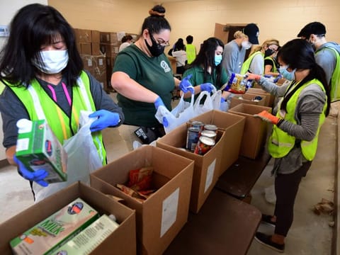 COVID-19: Volunteers in masks and gloves pack groceries at a food bank