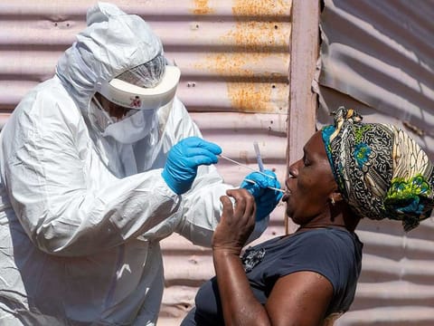 A woman opens her mouth for the health worker to collect a sample for coronavirus testing during the screening and testing campaign aimed to combat the spread of COVID-19 at Lenasia South, south Johannesburg, South Africa, Tuesday, April 21, 2020.