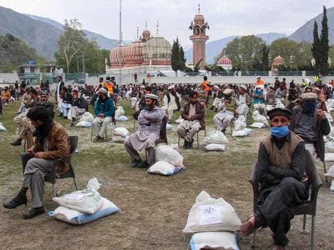 This photo taken on April 9, 2020 shows local residents collecting dry rations at a distribution point in Chitral in Khyber Pakhtunkhwa province, during a government-imposed nationwide lockdown against the COVID-19 coronavirus.
