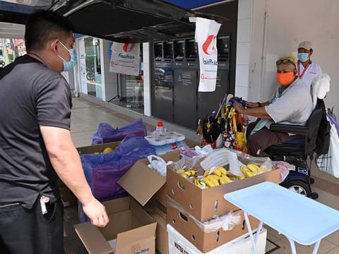 A resident (C), wearing a face mask as a preventive measure against the COVID-19 novel coronavirus, looks at groceries on offer from a mobile supermarket in Singapore on April 24, 2020.