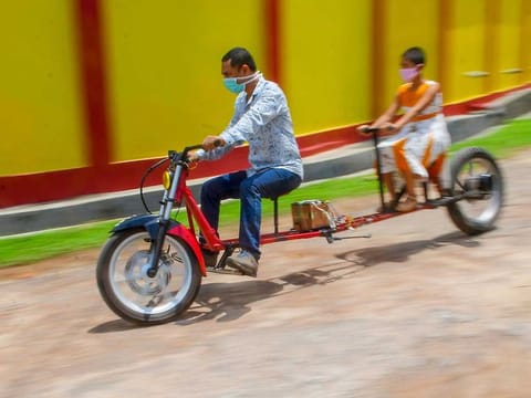 Self-made automobile engineer Partha Saha (L) tries his modified bike designed for social distancing as a preventive measure against the spread of the COVID-19 coronavirus with his daughter Pragya Saha in front of their house, in Aralia village on the outskirts of Agartala, India.