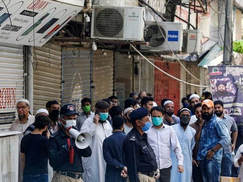 A police officer uses a megaphone to disperse shopkeepers who gathered to reopen their shops at a closed electronics market, as the lockdown continues during the efforts to stop the spread of the coronavirus disease, in Karachi, Pakistan.