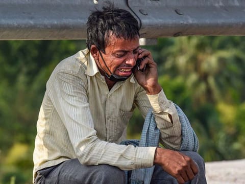A migrant worker cries on the side of a road in India