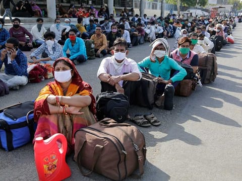 Migrant workers from other states trying to return to their homes wait for transportation to a train station in Ahmedabad, India, Sunday, May 17, 2020. Tens of thousands of migrant laborers have been returning from big cities to their villages after losing jobs because of a countrywide lockdown imposed in late March to contain the spread of the coronavirus.