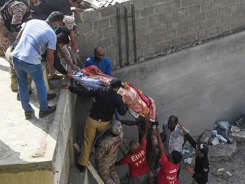 Rescue workers move a body from the site after a Pakistan International Airlines aircraft after crashed at a residential area in Karachi on May 22, 2020.