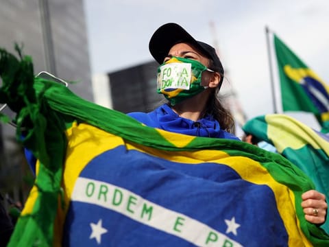 A supporter of Brazil's President Jair Bolsonaro wearing a protective mask with a sign attends a protest against quarantine measures amid the coronavirus disease (COVID-19) outbreak, in Sao Paulo, Brazil, May 24, 2020.