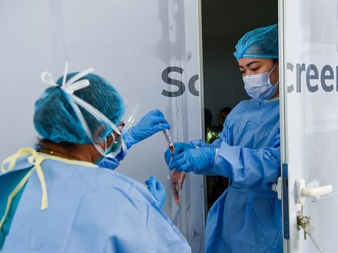 Paramedics collect swab samples at a coronavirus drive-through screening station in Sharjah Golf and Shooters Club.