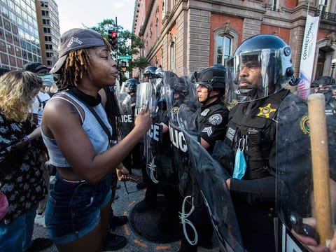 Demonstrators talk to police in riot gear as they protest the death of George Floyd, on May 30, 2020, near the White House in Washington. Floyd died after being restrained by Minneapolis police officers on Memorial Day.