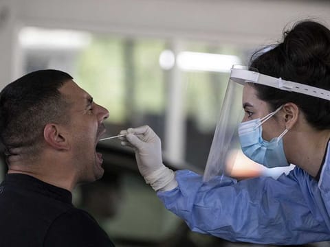 A public health worker collects an oral swab sample from a man to test for Covid-19 at the Greek-Bulgarian border crossing in Promachonas, Greece, on Wednesday, June 24, 2020. Europe is trying to revive domestic economies as the summer tourist season gets underway while guarding against a second wave of infections.