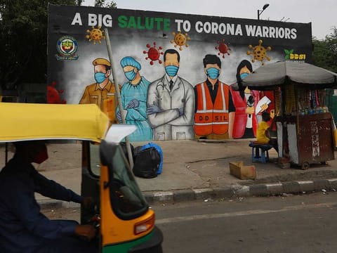 An autorickshaw drives past a graffiti thanking frontline workers in the fight against the coronavirus, in New Delhi