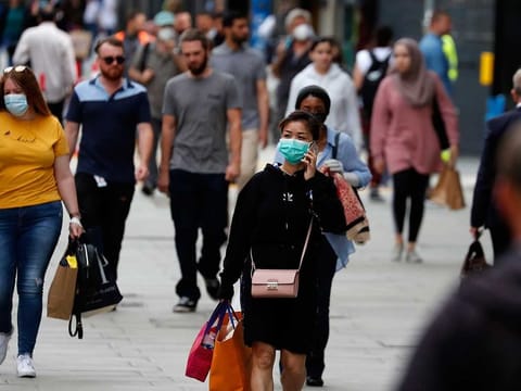 Shoppers walk along Oxford Street in London, Tuesday, July 14, 2020. Britain's government is demanding people wear face coverings in shops as it has sought to clarify its message after weeks of prevarication amid the COVID-19 pandemic.