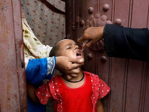 A girl receives polio vaccine drops, during an anti-polio campaign, in a low-income neighbourhood in Karachi, Pakistan July 20, 2020.