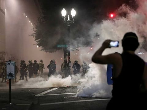 A demonstrator holds a mobile phone in front of federal law enforcement officials during a protest against racial inequality in Portland, Oregon, U.S., July 21, 2020.