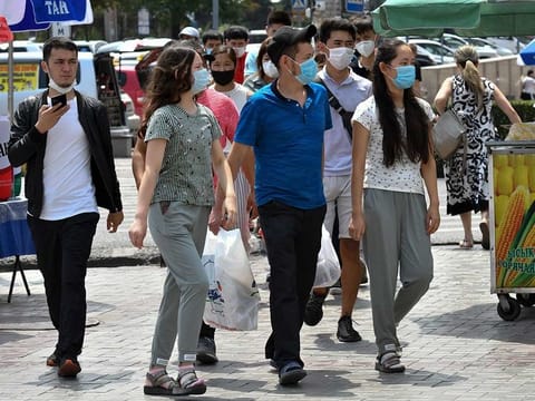 Youths in face masks walk through a street market in Bishkek, Kyrgyzstan, Friday, July 24, 2020.