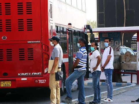 Expats wait to board a bus at a station in Kuwait City. An expatriate’s personal health insurance does not replace obligatory health insurance which will be necessary for renewing residency permit.