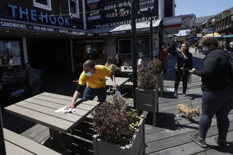 A man wears a face mask while cleaning an outdoor dining table (File image)