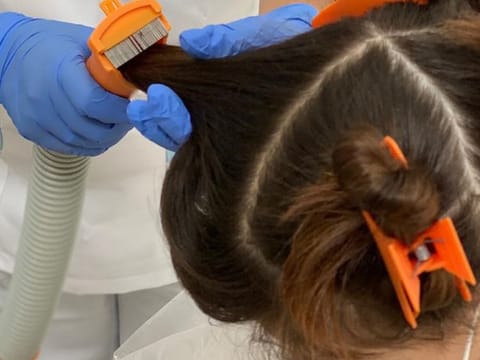 A little girl with lice in her hair being treated at No More Lice, Dubai