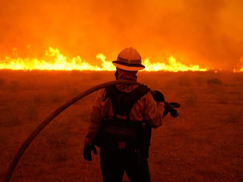 Alexis Miller of Los Angeles County Fire holds a water hose while protecting a home from the advancing Bobcat Fire along Cima Mesa Rd. Friday, Sept. 18, 2020, in Juniper Hills, California.
