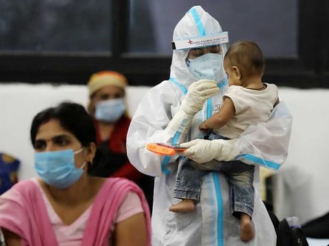A medical worker in personal protective equipment (PPE) plays with a child of a woman recovering inside a quarantine centre for the coronavirus disease (COVID-19) patients amidst the spread of the disease at an indoor sports complex in New Delhi, India.