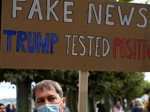 A demonstrator holds up a placard reading 'Fake news in Konstanz, southern Germany, on October 3, 2020.
