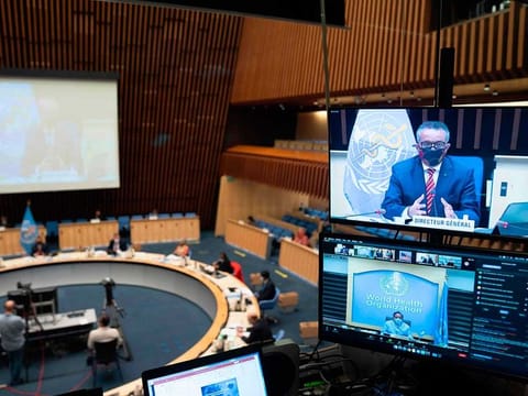 This handout picture taken and released by the World Health Organisation on October 5, 2020 shows WHO Director-General Tedros Adhanom Ghebreyesus wearing a protective face mask delivering a speech on a TV screen during a WHO executive board special session on the Covid-19 response at the health agency's headquarters in Geneva.