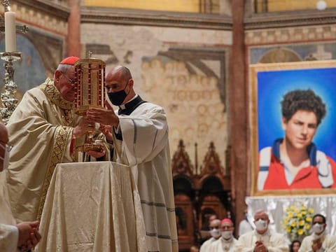 Cardinal Agostino Vallini, left, holds a relic of 15-year-old Carlo Acutis, an Italian boy who died in 2006 of leukaemia, during his beatification ceremony celebrated in the St. Francis Basilica, in Assisi, Italy, Saturday, Oct. 10, 2020.