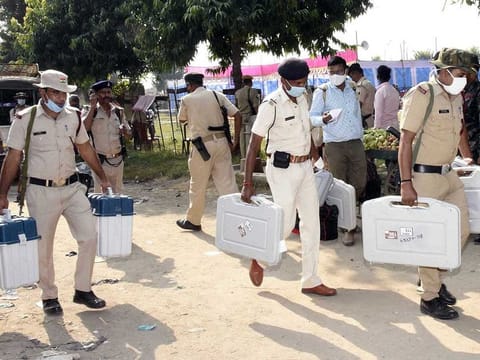 Security personnel carrying Electronic Voting Machines (EVMs) on the eve of the first phase of Bihar Assembly Elections, at Paliganj in Patna district on Tuesday.